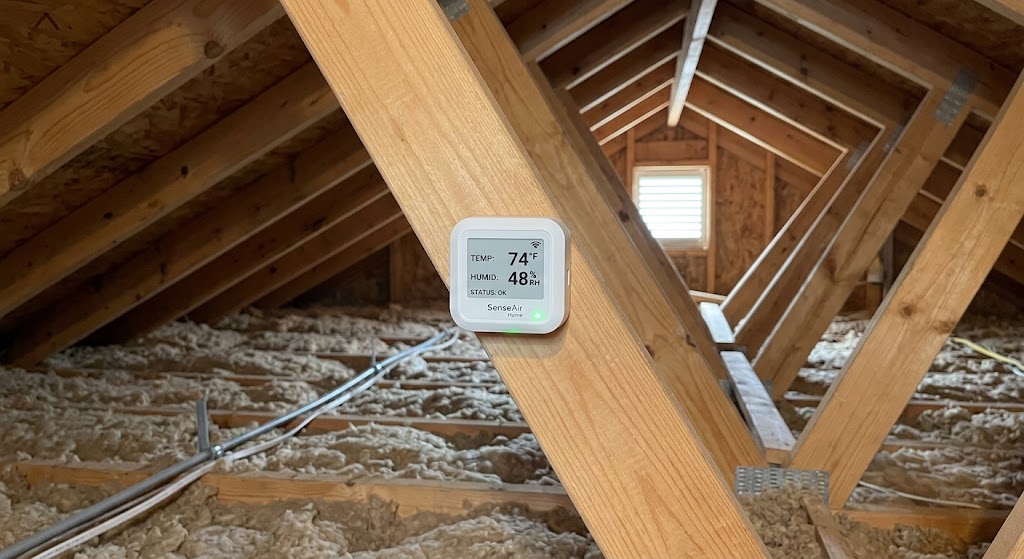 Smart temperature and humidity sensor monitoring conditions in a clean residential attic near roof framing